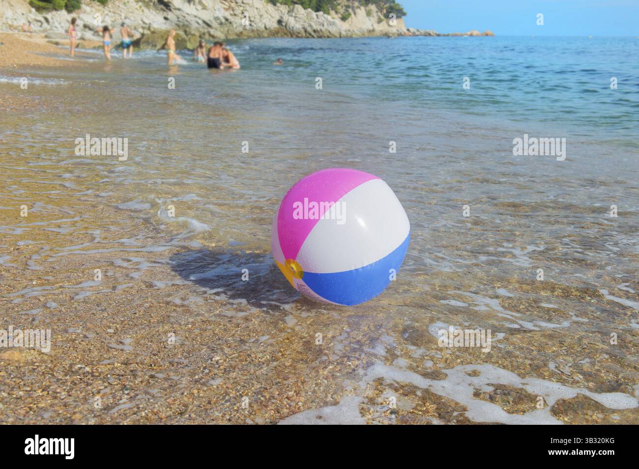 Ballon de plage gonflable coloré jouant avec le surf et la mer Banque D'Images