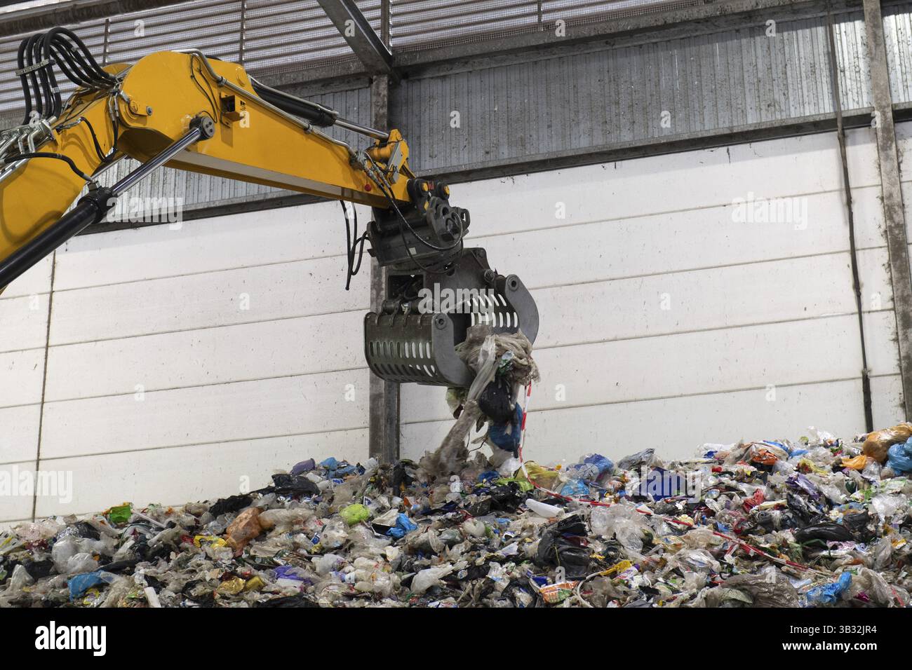 Matériau de recyclage plastique collecté avec une grue jaune Banque D'Images