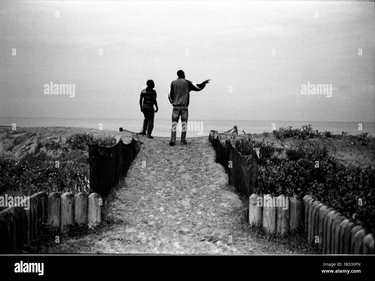 Jan 4, 2016 - South Beach, KwaZulu-Natal, Afrique du Sud - Deux hommes pause pendant la marche sur les dunes sur South Beach. South Beach est une partie de la ville de Durban sans interruption la plus longue étendue de plage de sable. La ville de Durban est sur la côte est de l'Afrique du Sud et les gens ici sont lavés avec de l'eaux chaudes de l'Océan Indien. Au nord de cette étendue de sable sont des plages avec la société hang out cafe. Au sud il y a une jetée avec le quartier haut Moyo's Restaurant à elle est la fin et l'uShaka Marine World et le secteur complexe de la mer et surf clubs de la plage les vesces. Parier Banque D'Images