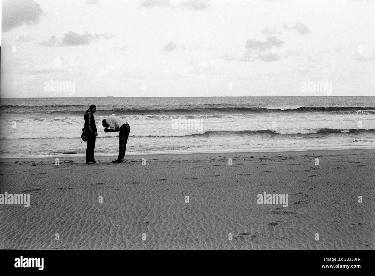 Jan 4, 2016 - South Beach, KwaZulu-Natal, Afrique du Sud - Deux jeunes amants d'allumer une cigarette dans la lumière du soir. South Beach est une partie de la ville de Durban sans interruption la plus longue étendue de plage de sable. La ville de Durban est sur la côte est de l'Afrique du Sud et les gens ici sont lavés avec de l'eaux chaudes de l'Océan Indien. Au nord de cette étendue de sable sont des plages avec la société hang out cafe. Au sud il y a une jetée avec le quartier haut Moyo's Restaurant à elle est la fin et l'uShaka Marine World et le secteur complexe de la mer et surf clubs de la plage les vesces. Entre Banque D'Images