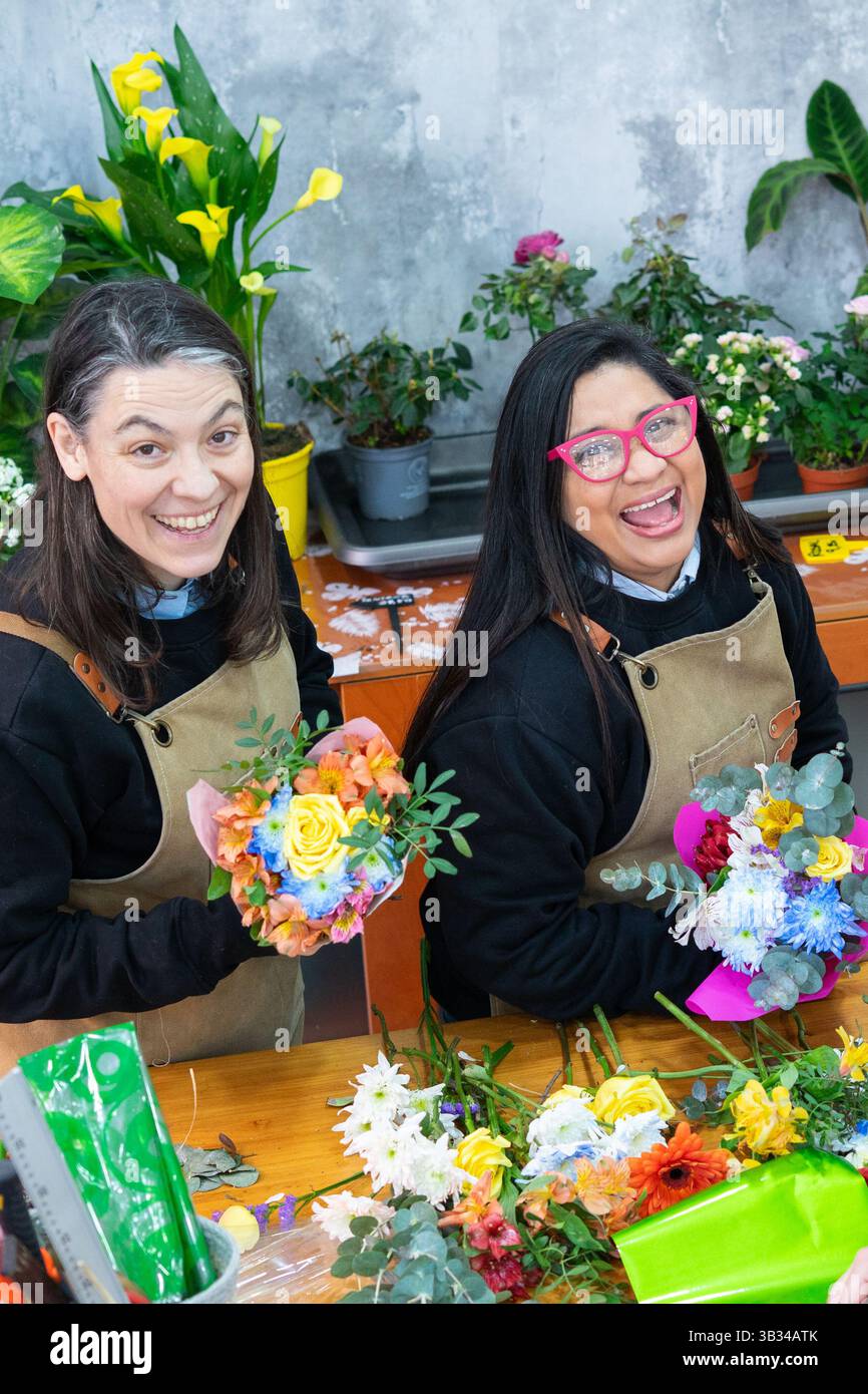 Deux fleuristes heureux montrant des bouquets qu'ils viennent de préparer dans leur fleuriste Banque D'Images