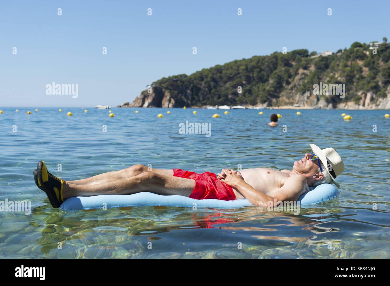 L'homme a pris sa retraite avec couchage lit gonflable flottant dans la mer Banque D'Images