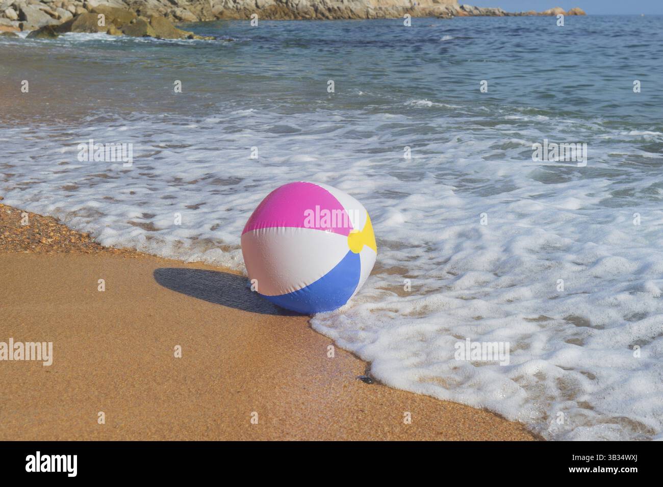 Ballon de plage gonflable coloré jouant avec le surf et la mer Banque D'Images