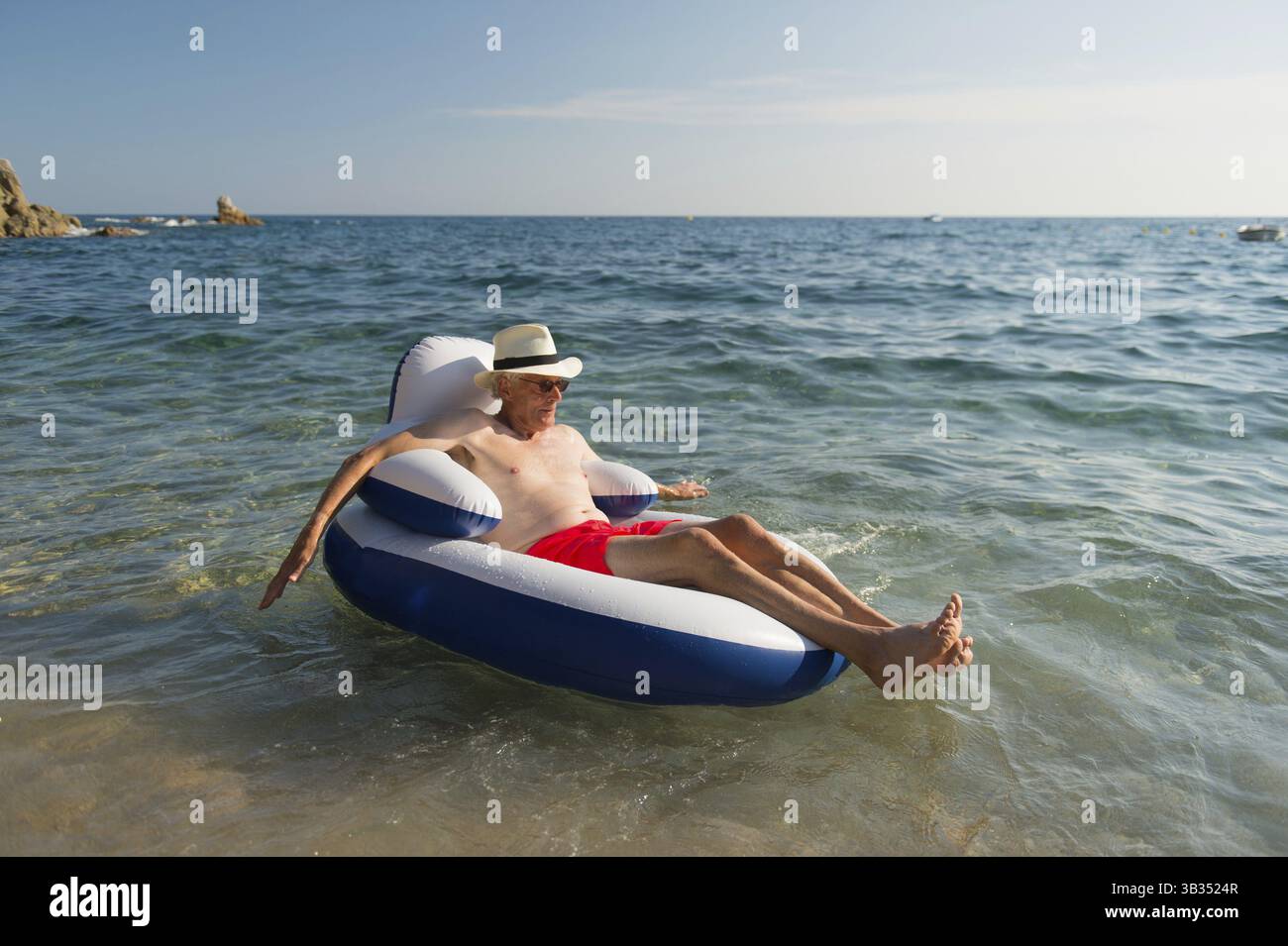 Senior en vacances flottant à la présidence dans la mer Banque D'Images