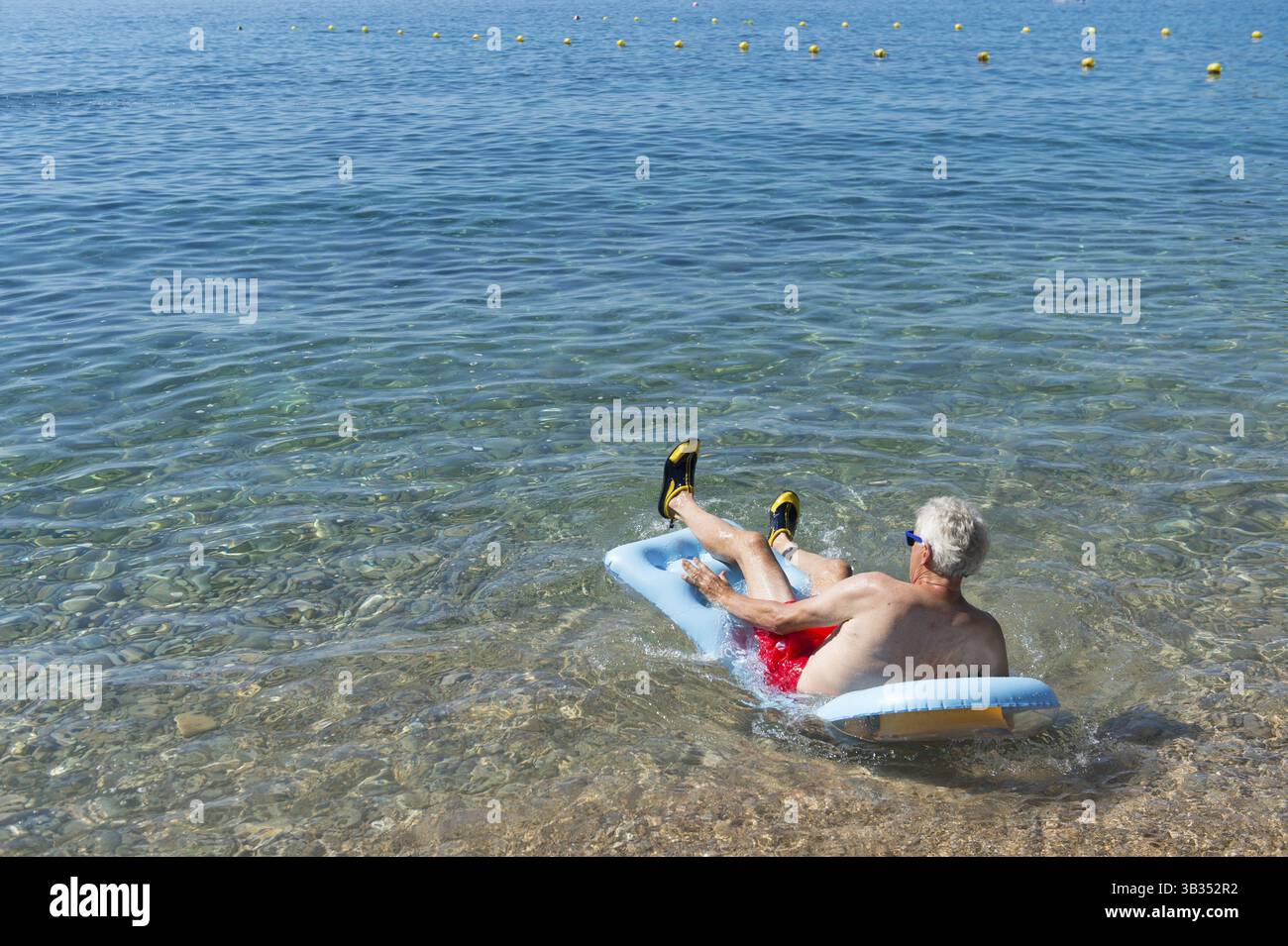 Libre de jouer avec lit gonflable flottant dans la mer Banque D'Images