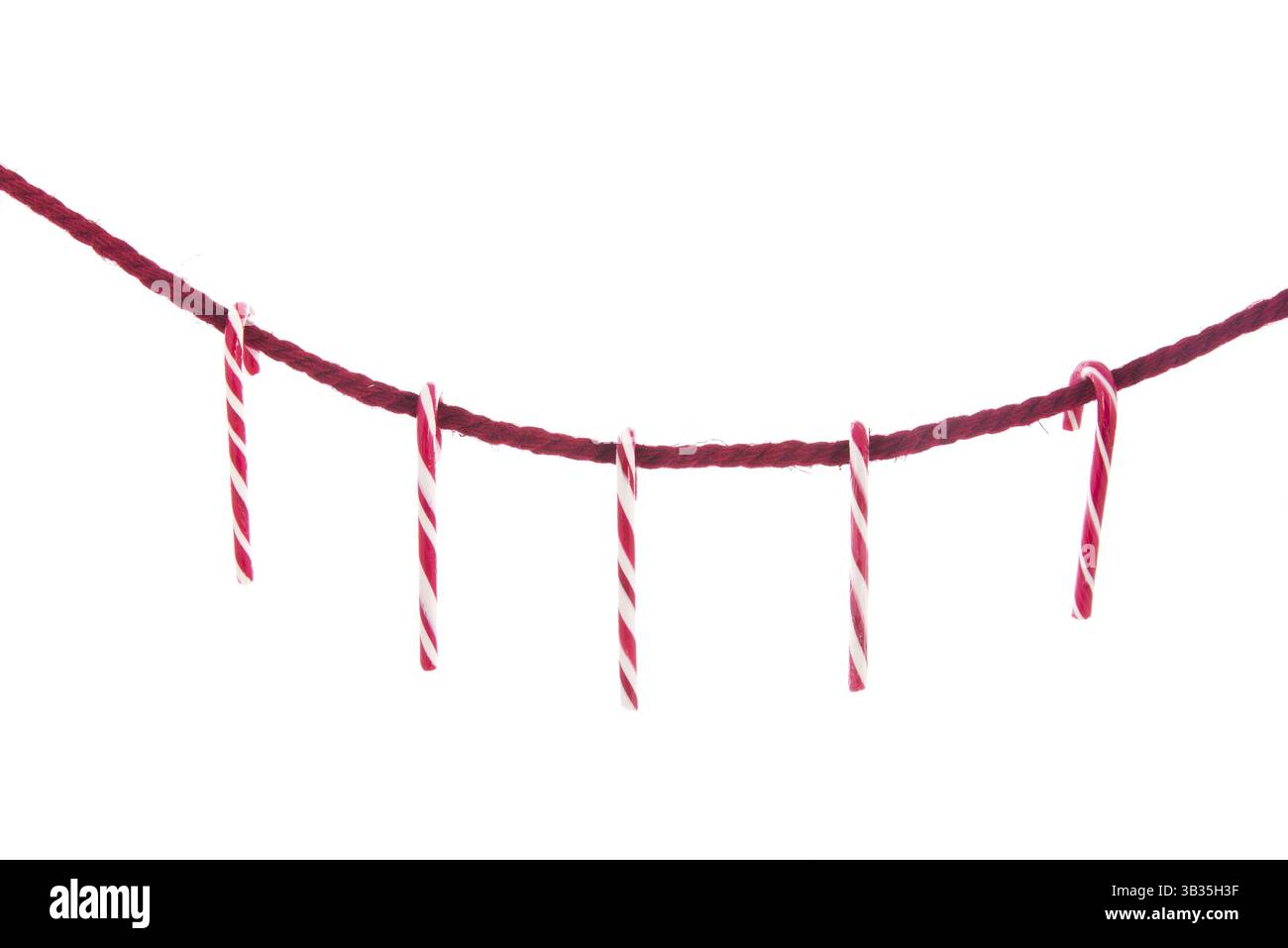 Corde rouge simple avec Cannes de Noël isolé sur blanc Banque D'Images