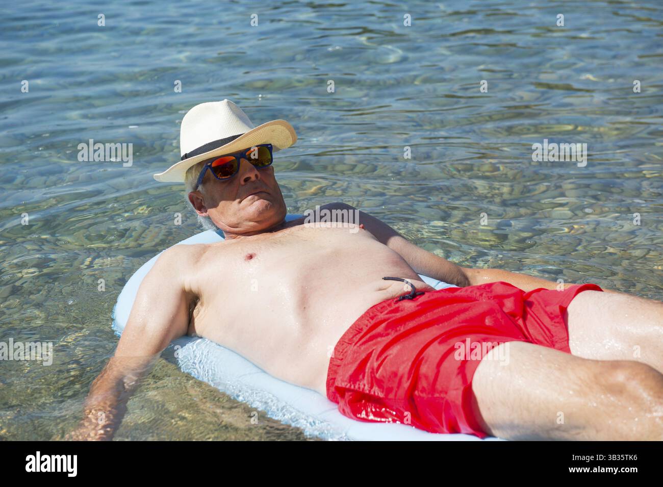 L'homme à la retraite et de couchage lit gonflable flottant sur le flottant dans la mer Banque D'Images