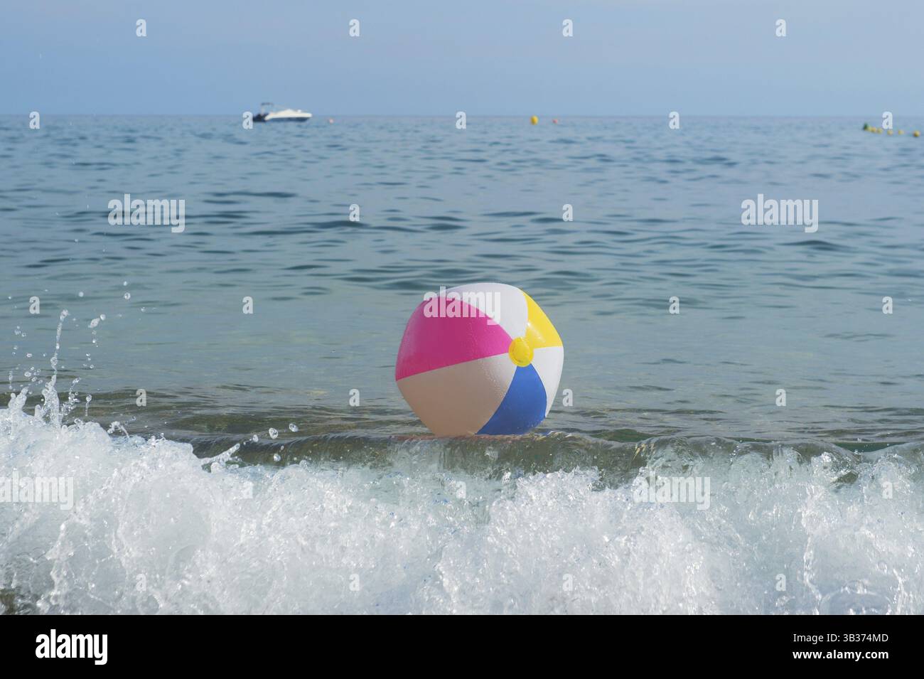 Ballon de plage gonflable coloré jouant avec le surf et la mer Banque D'Images