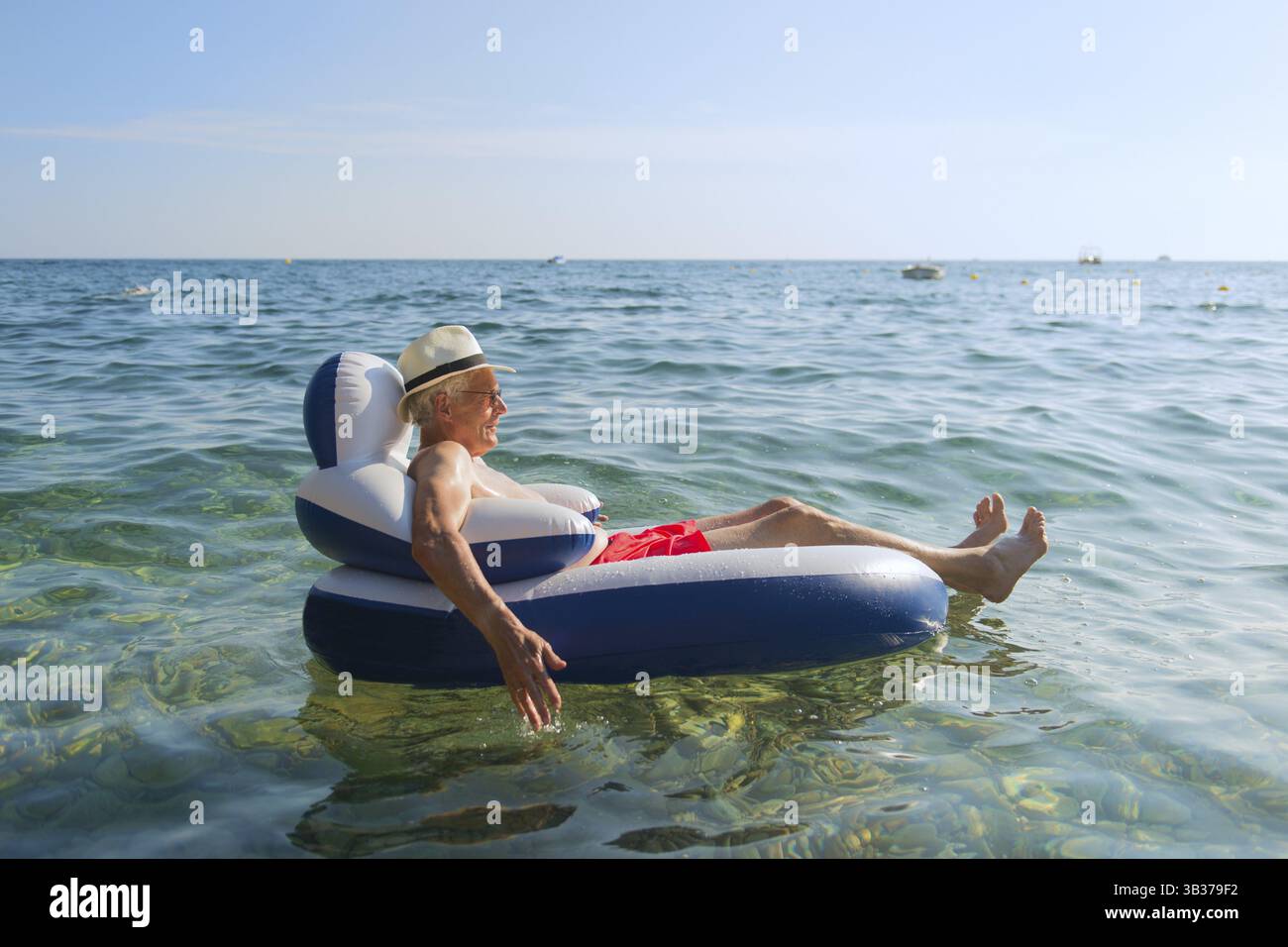 Senior en vacances flottant à la présidence dans la mer Banque D'Images