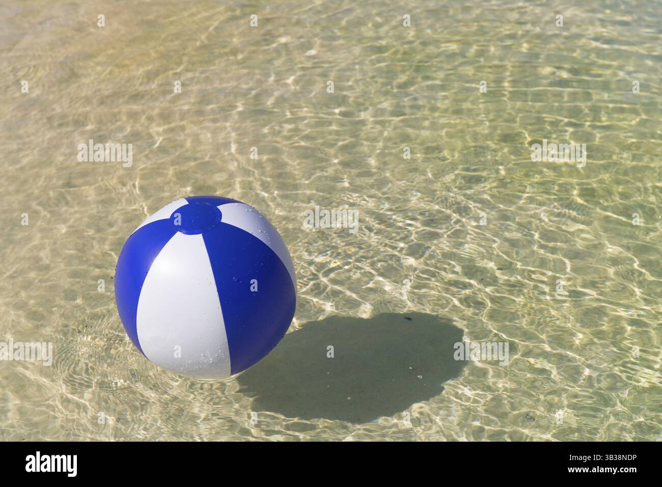 Ballon de plage bleu et blanc gonflable flottant sur l'eau Banque D'Images