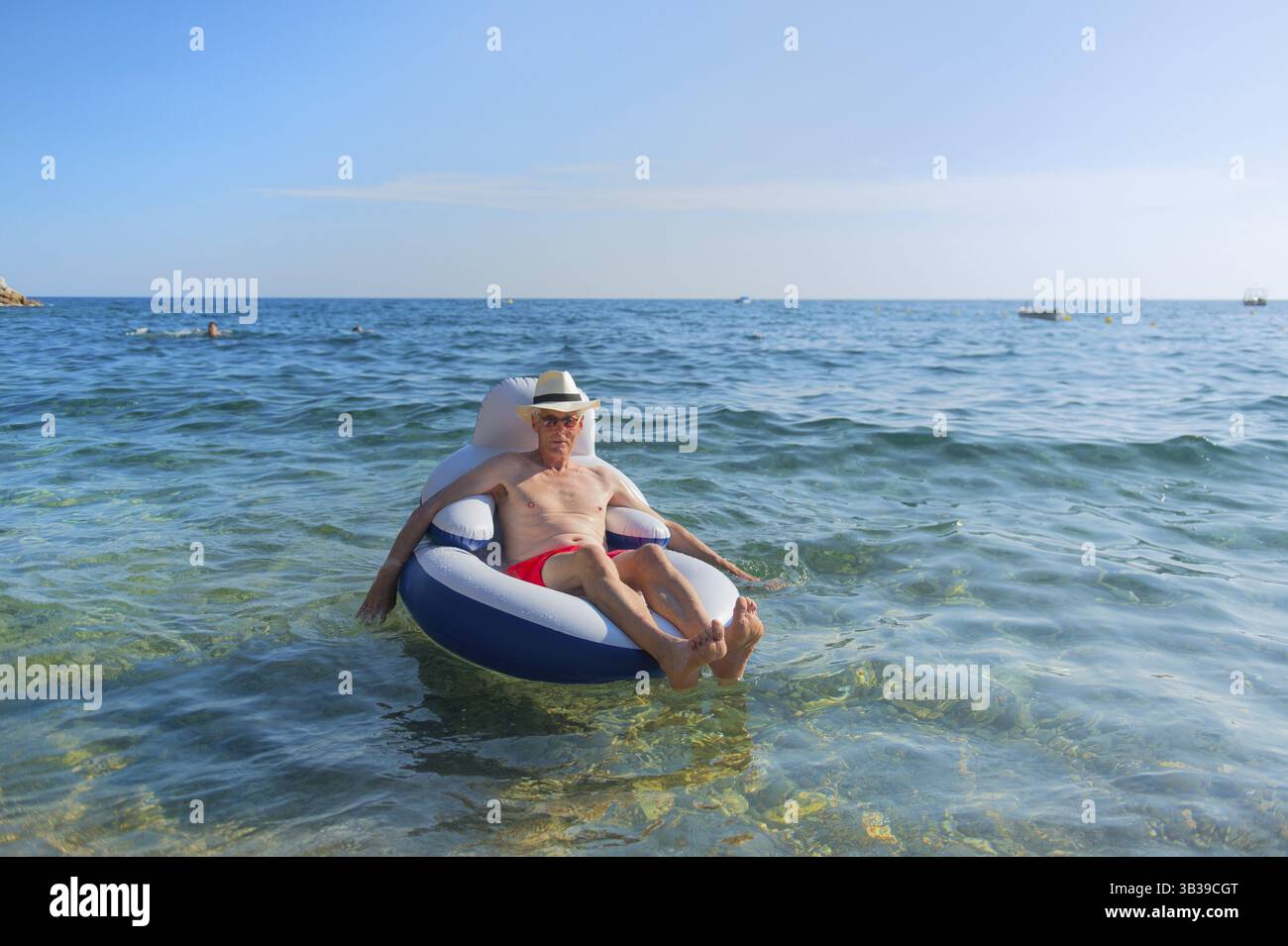 Senior en vacances flottant à la présidence dans la mer Banque D'Images