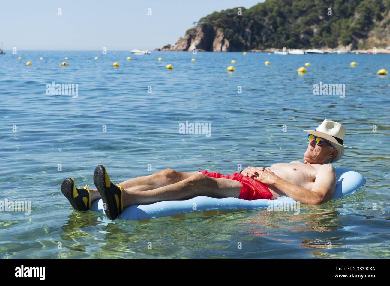 L'homme à la retraite portant sur lit gonflable flottant dans la mer Banque D'Images