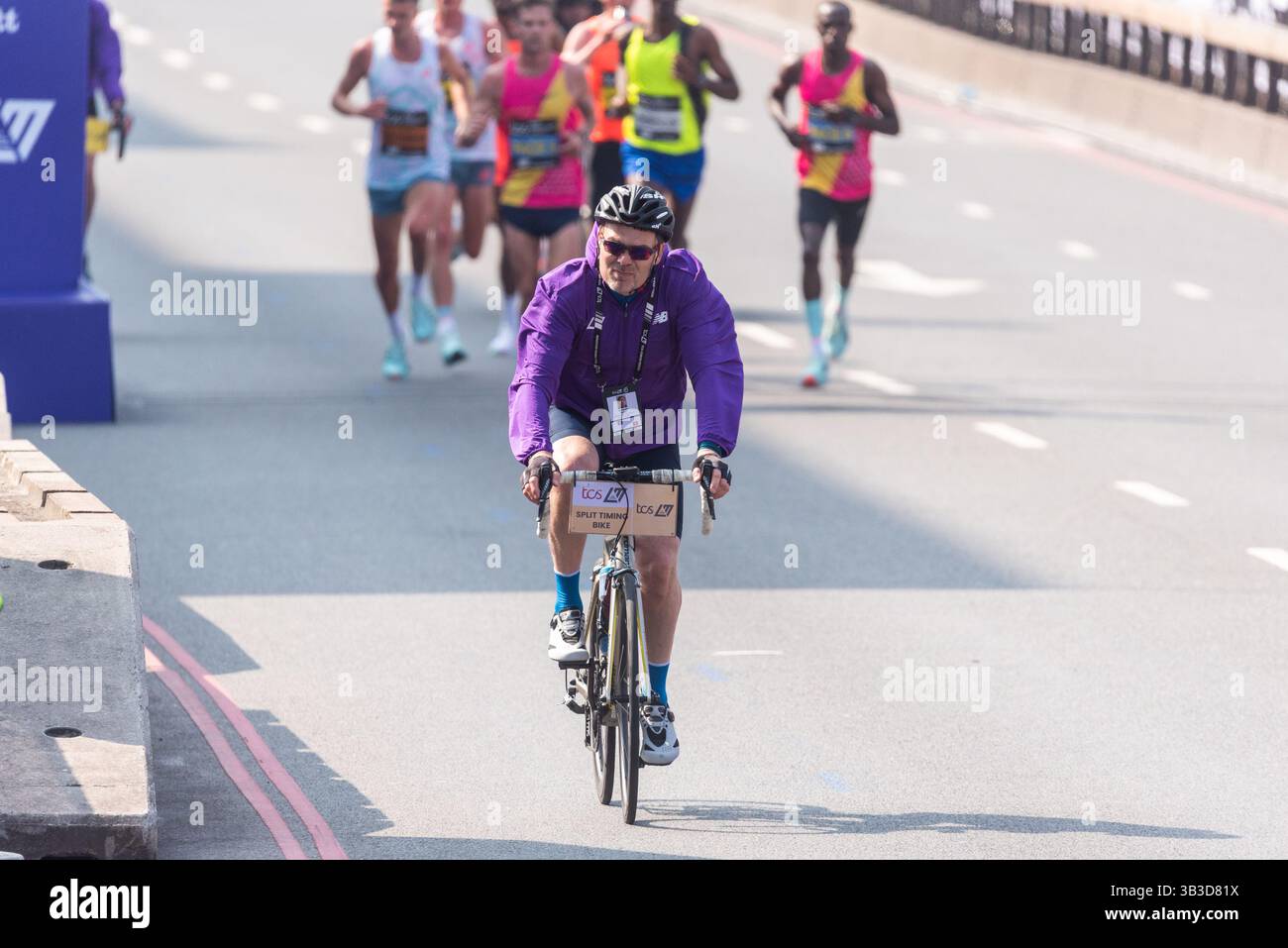 Cycliste à chronométrage divisé devant les athlètes participant au marathon TCS de Londres 2025, en passant par Tower Hill, Londres, Royaume-Uni. Officiel Banque D'Images Cycliste à chronométrage divisé devant les athlètes participant au marathon TCS de Londres 2025, en passant par Tower Hill, Londres, Royaume-Uni. Officiel Banque D'Images