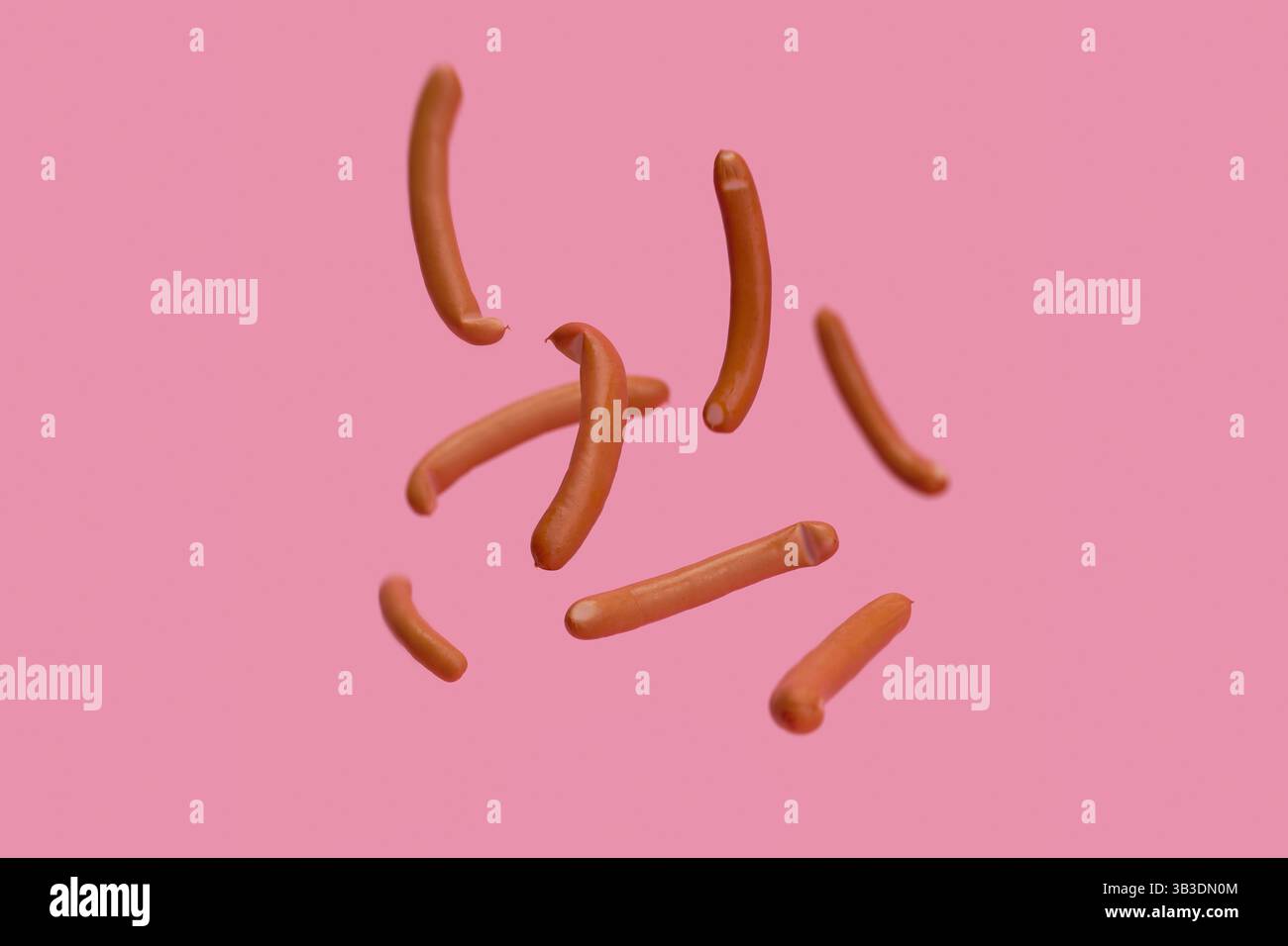 Saucisses bavaroises tombant sur fond rose Banque D'Images