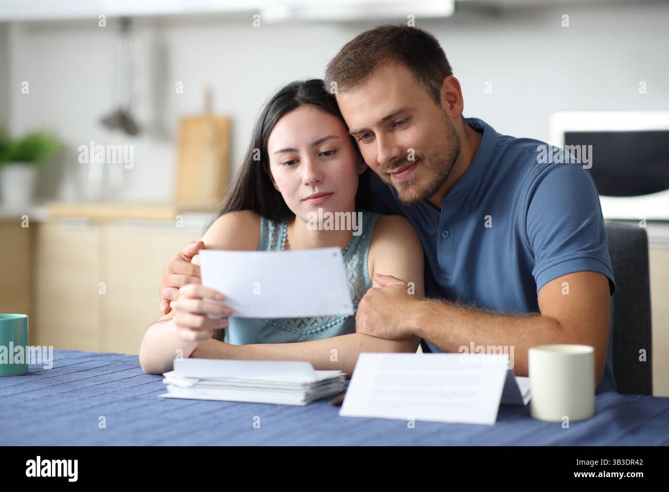 Couple interracial satisfait dans la lettre de vérification d'amour dans la cuisine à la maison Banque D'Images