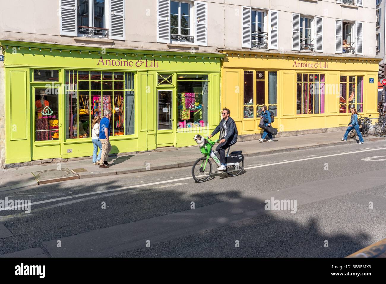Une scène de rue dans le 10ème arrondissement de Paris. Façade de magasin verte et jaune. Vie quotidienne parisienne. Chien dans un panier sur un vélo. Cyclistes et marcheurs Banque D'Images