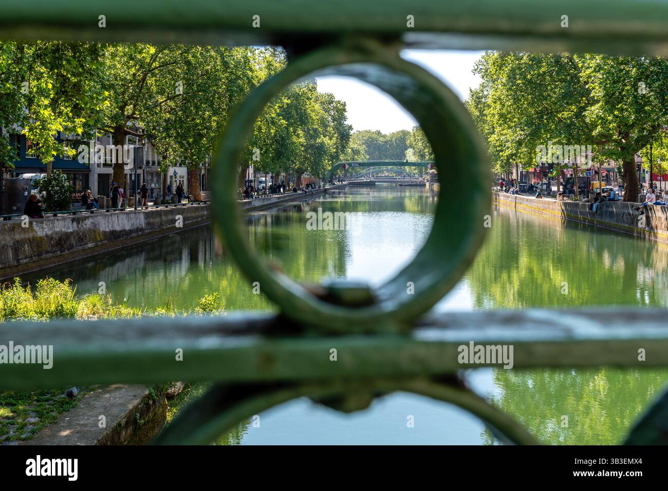 Paris, France, 04.28.2025 personnes profitent d’une journée chaude le long du canal Saint Martin dans le 10ème arrondissement. Vue depuis un pont. Banque D'Images