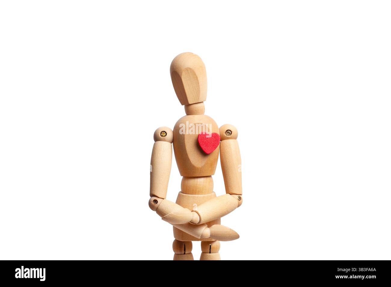 Un mannequin jouet en bois avec un coeur rouge sur sa poitrine isolé sur fond blanc Banque D'Images