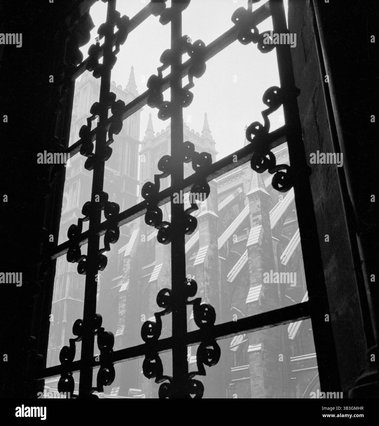 Regardant à travers une grille décorative de fenêtre en fer forgé vers la façade sud de la nef de l'abbaye de Westminster, Londres, 1947-1957. Banque D'Images