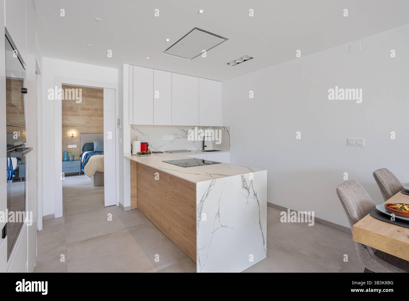 Cuisine élégante avec îlot de marbre, plaque de cuisson intégrée et vue sur une chambre confortable. Banque D'Images