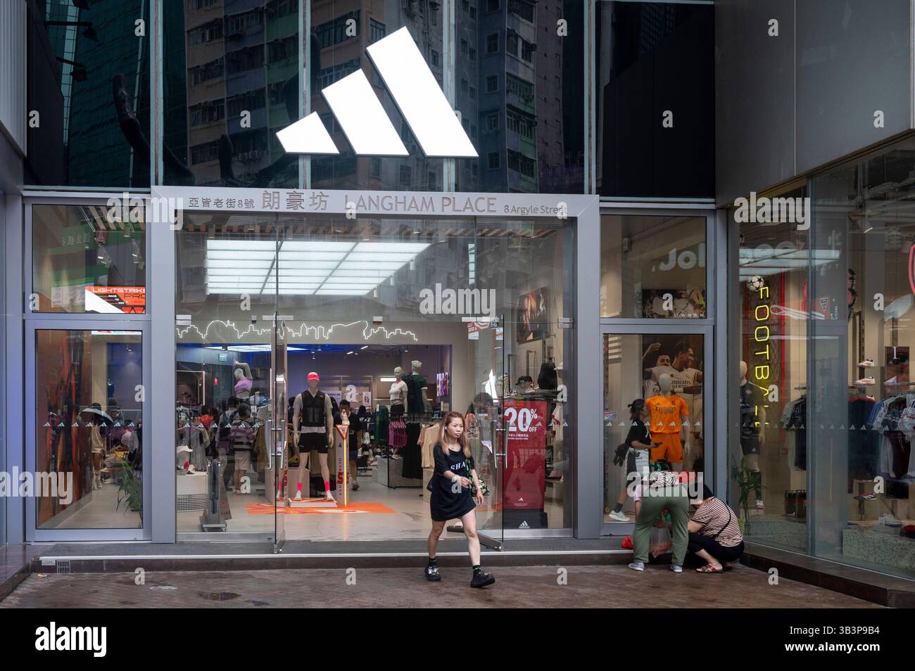Les acheteurs sont vus à l'extérieur du magasin de la multinationale allemande de vêtements de sport Adidas dans un centre commercial de Hong Kong. Banque D'Images