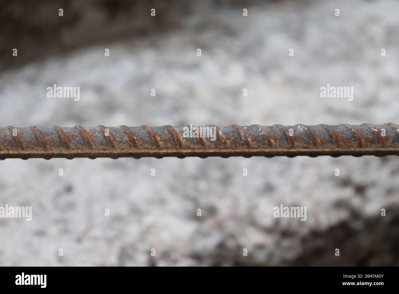 Le cliché détaillé à hauteur des yeux présente les textures des barres d'armature en acier corrodé, l'alignement horizontal avec un peu de rouille, offrant une sensation industrielle et brute. Banque D'Images