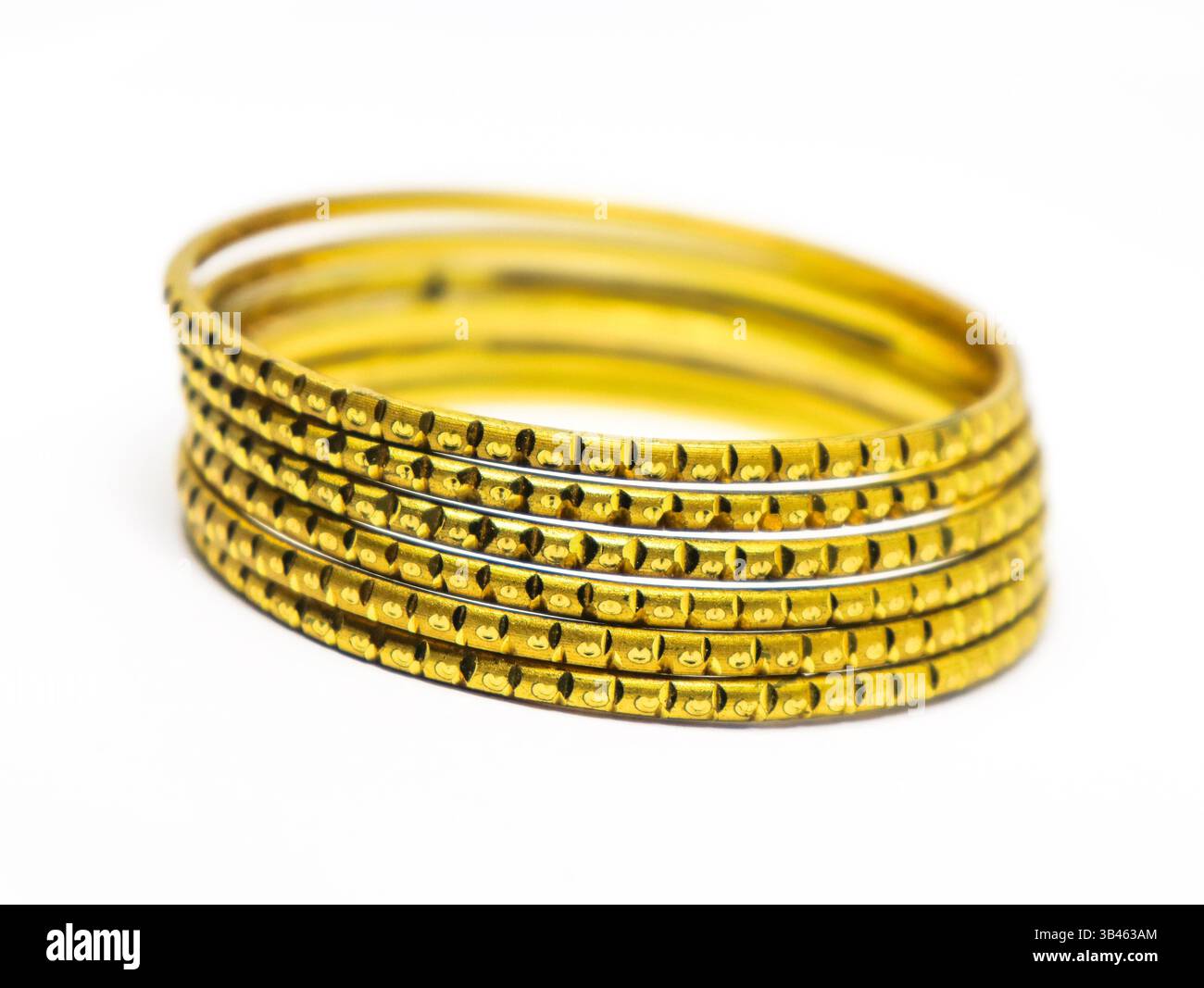 Collection de bracelets teints or superposés, détails complexes de conception en métal or affichés sur une surface blanche. Banque D'Images