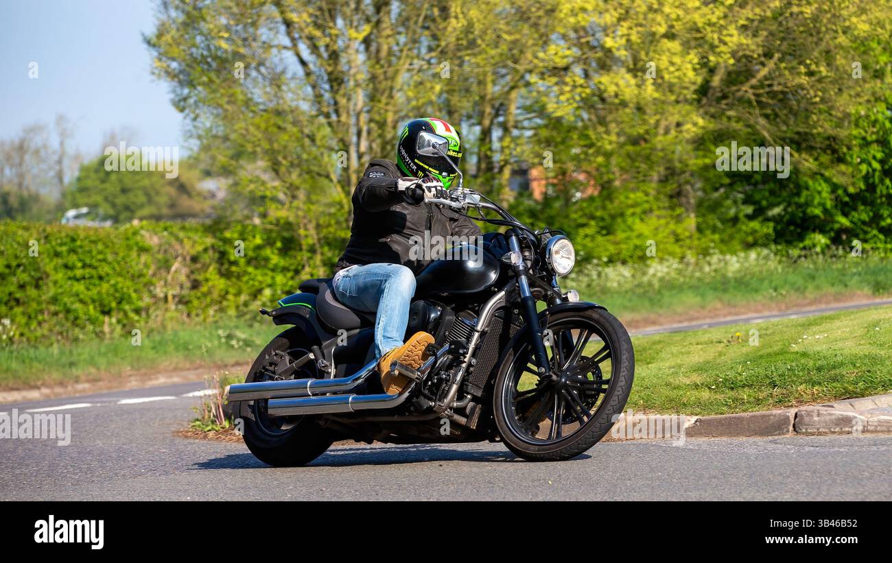 Whittlebury,Northants.,.UK - 27 avril 2025 : homme conduisant une moto personnalisée Kawasaki vn 900 2010 sur une route de campagne anglaise. Banque D'Images