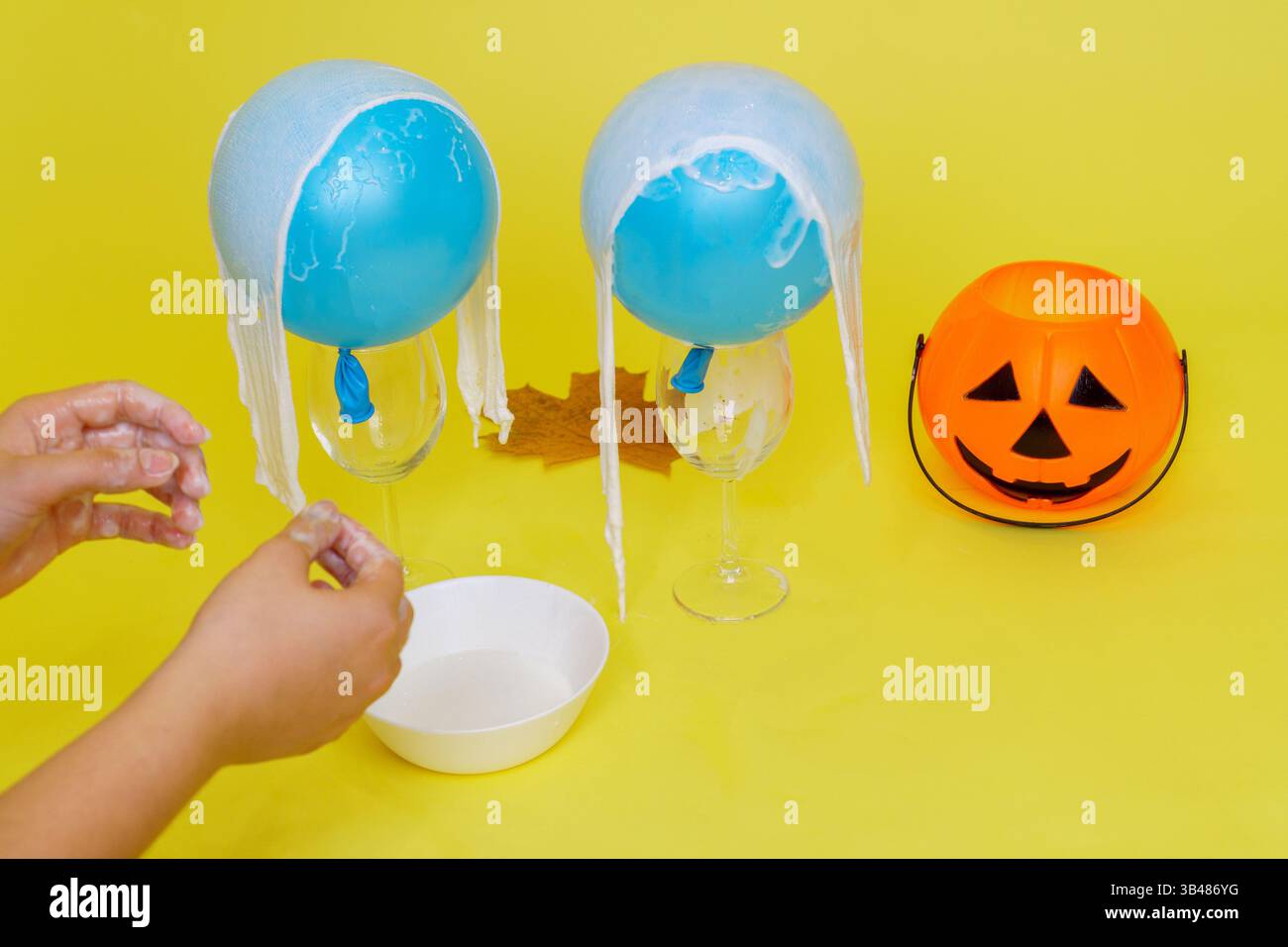 Bricolage artisanal fantôme d'Halloween fabriqué à partir de bandages et de colle. Nous avons mis des bandages dans la colle sur les balles. Étape 3. Banque D'Images