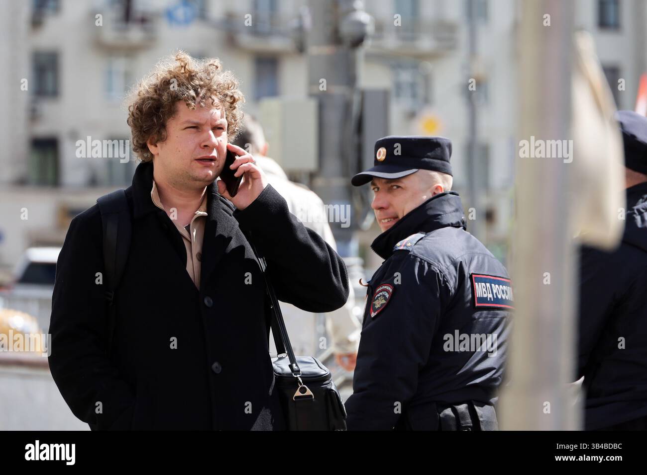 Homme parlant sur smartphone tout en marchant dans la rue sur fond de policier Banque D'Images