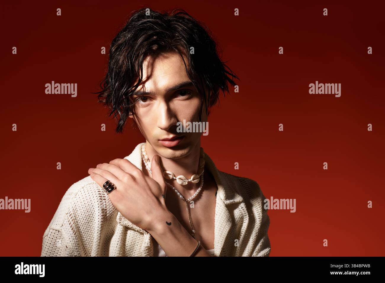 Jeune homme respire la confiance et le style dans une tenue d'été sur un fond chaud. Banque D'Images