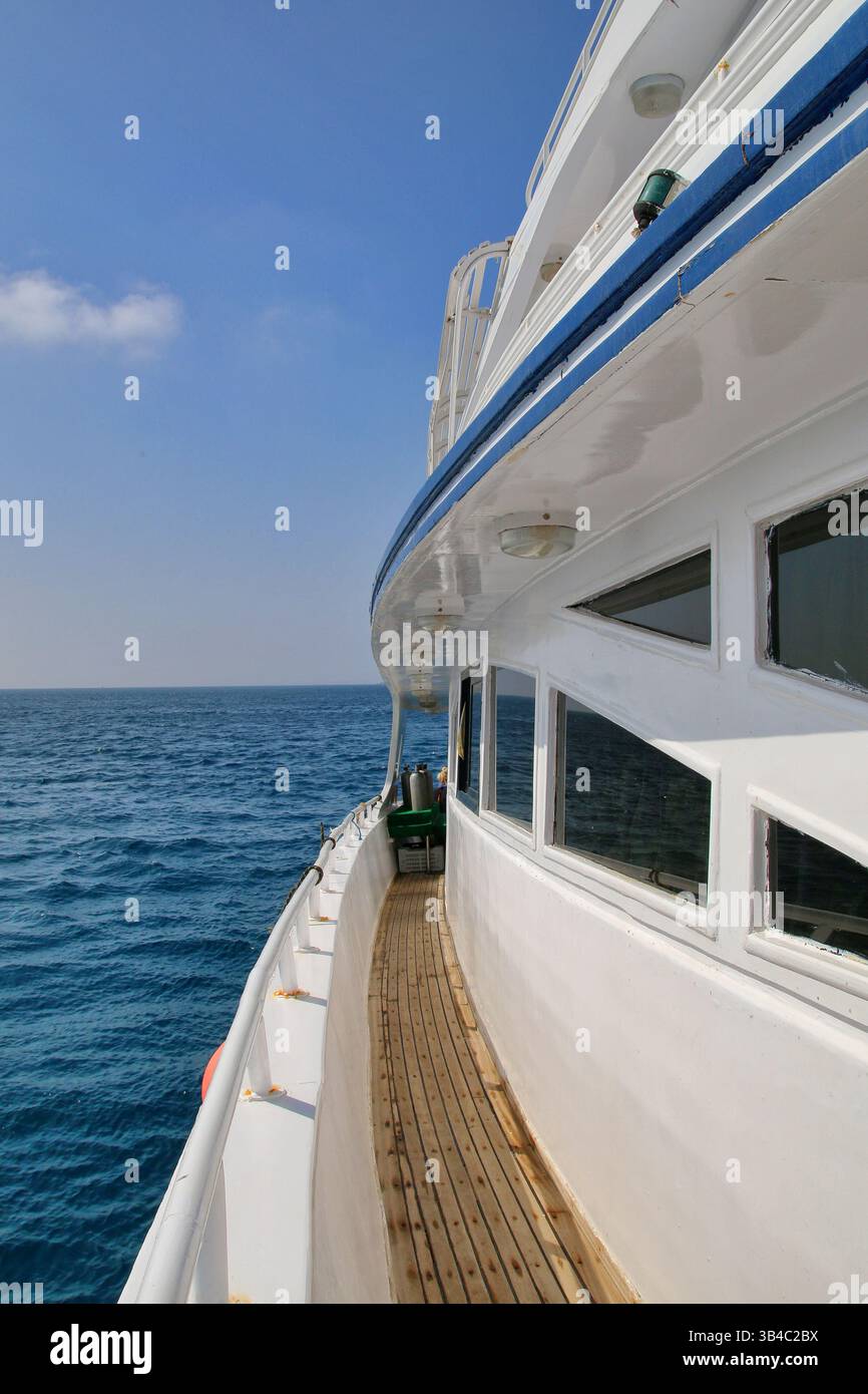 Vue le long du pont en bois d'un yacht blanc naviguant sur la mer Rouge, Egypte. Composition propre avec des reflets doux et des couleurs maritimes vives. Banque D'Images