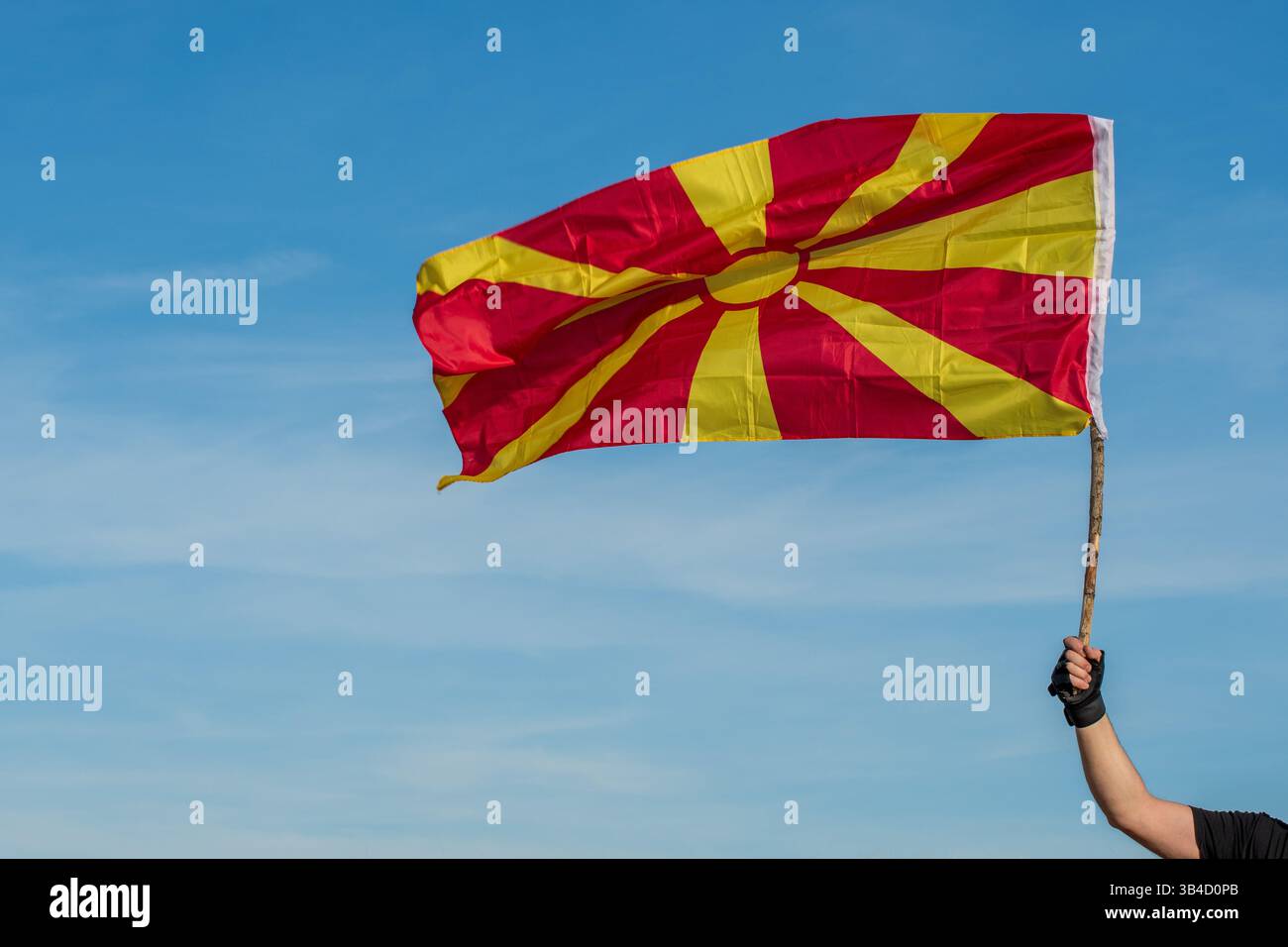 Waving Pride : drapeau macédonien contre le ciel bleu. Banque D'Images