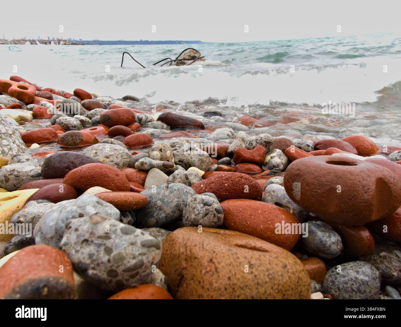 Surface très détaillée du mélange de galets créé par la force de l'eau. Le littoral de l'Ontario affiche une harmonie de couleurs façonnée par le temps et la marée. Banque D'Images