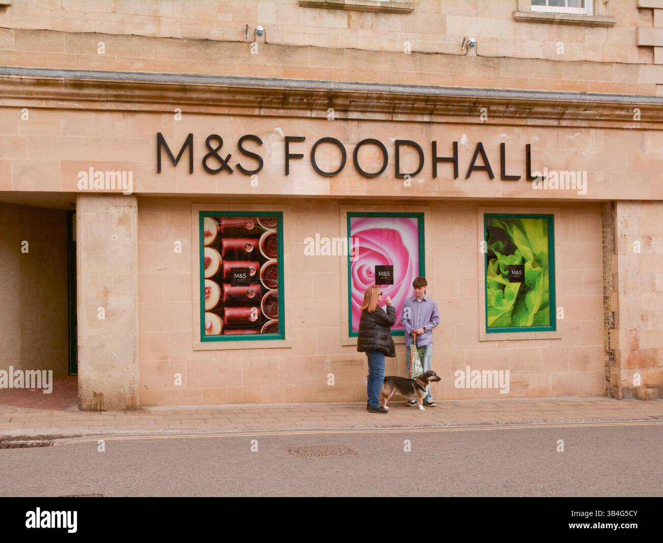 Promeneurs de chiens ayant une conversation devant un Foodhall M&S à Stamford, Lincolnshire, Angleterre Banque D'Images