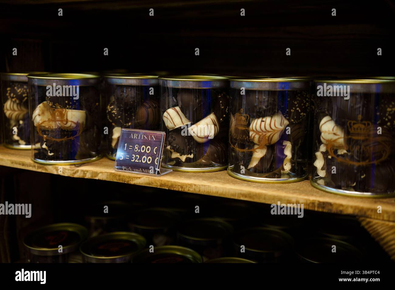 Bruxelles, Belgique. 20 mars 2025 - des canisters de chocolat belge artisanal alignent une étagère en bois dans une boutique à Bruxelles. Banque D'Images