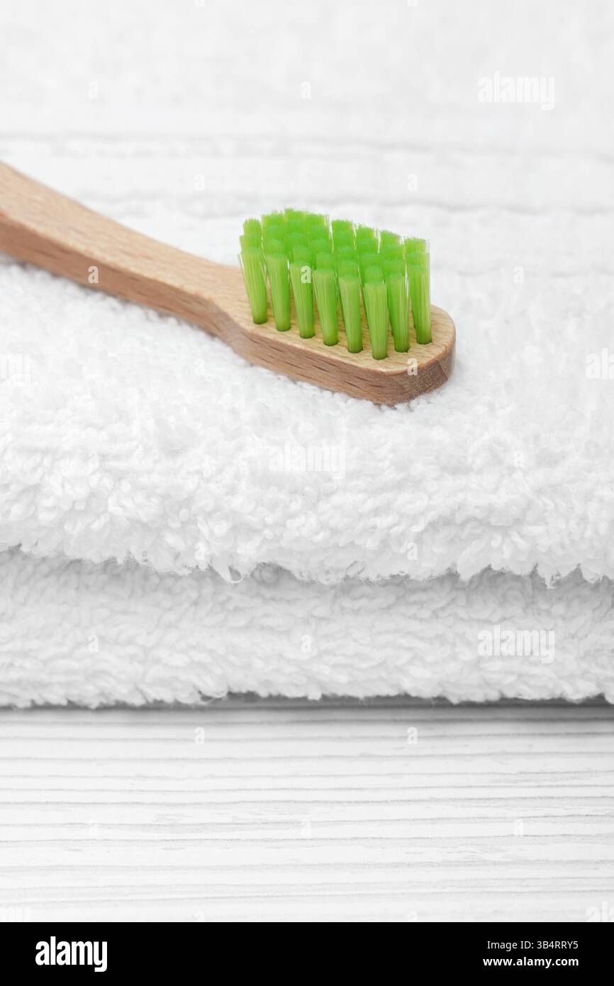 Brosse à dents écologique en bois avec des poils verts sur une serviette blanche. Hygiène buccale. Banque D'Images