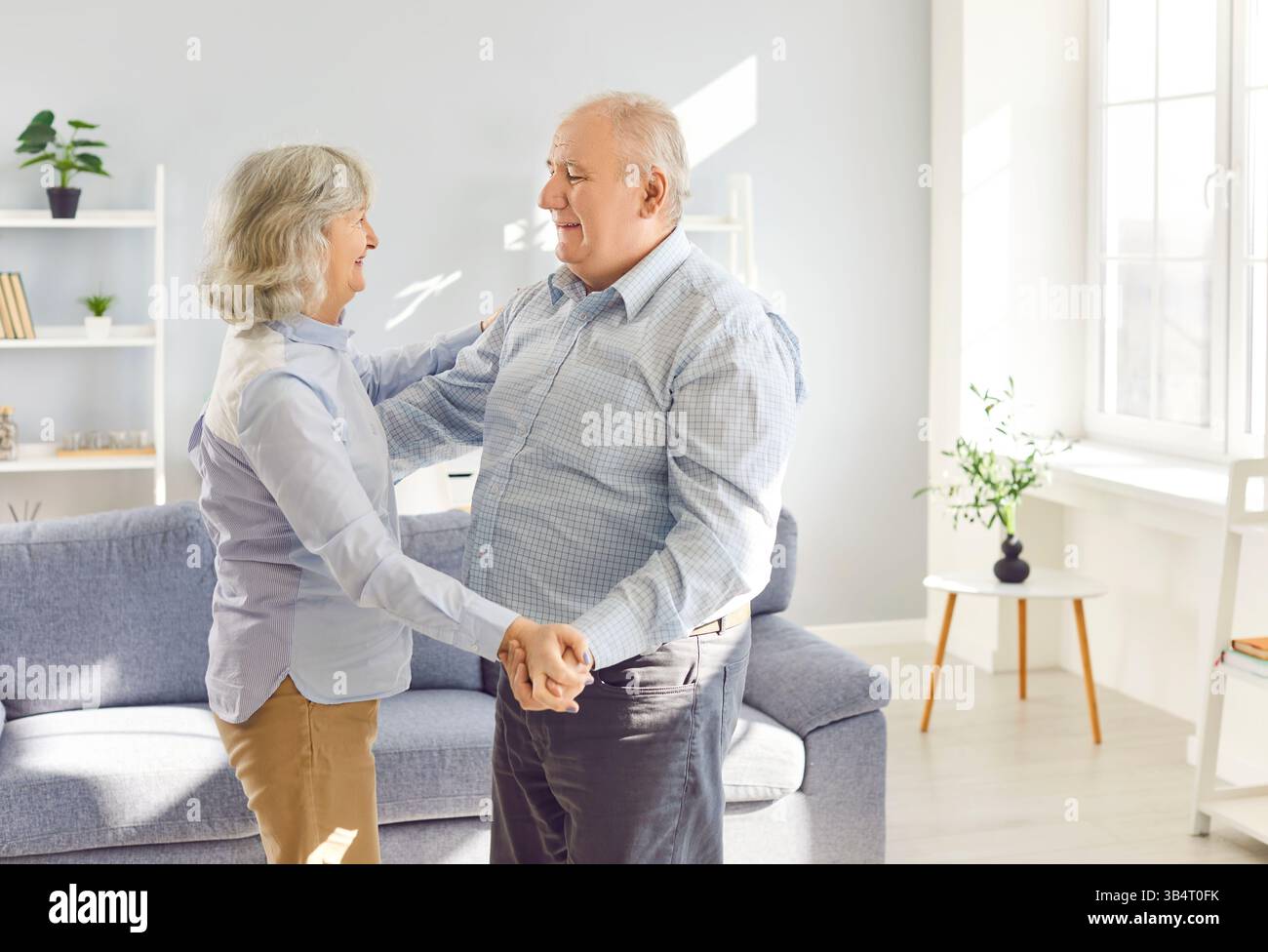 Heureux senior danse à la maison joyeux conjoints retraités mari et femme riant dansant dans le salon Banque D'Images