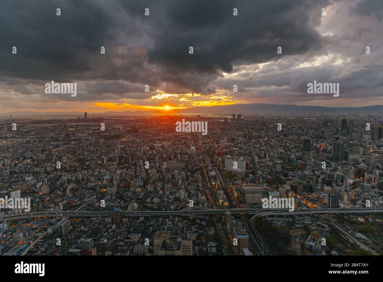 Vue aérienne du paysage urbain d'Osaka lors d'un coucher de soleil dramatique orageux montrant les tours des autoroutes et les quartiers résidentiels denses Banque D'Images