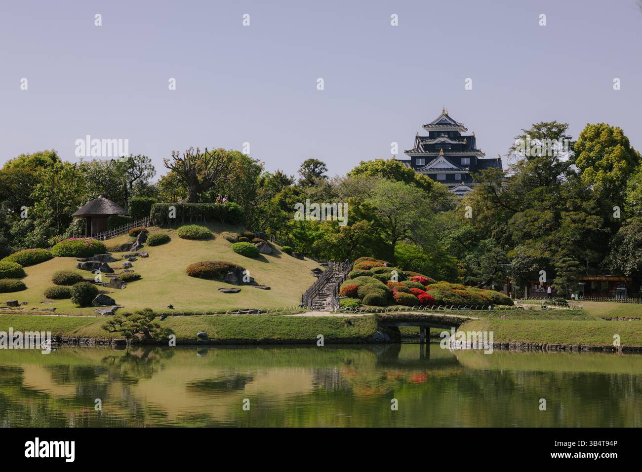 Vue sur le paysage du jardin Okayama Korakuen surplombant le château d'Okayama, avec étang japonais traditionnel et cerisiers en fleurs d'érable Banque D'Images