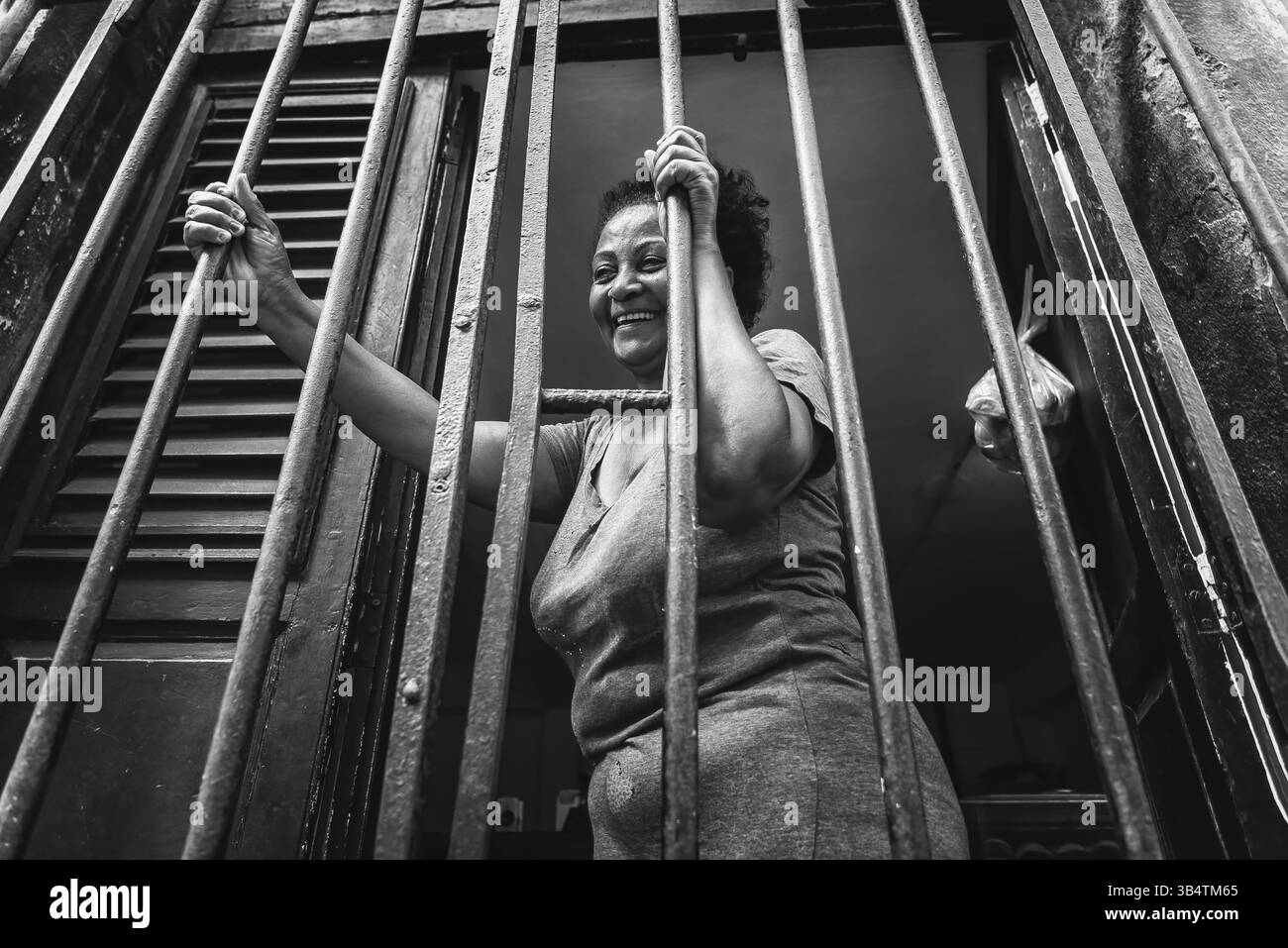 La Havane, Cuba - 04 février 2023 : une femme cubaine regarde à travers des portes barrées à la Havane, capturant l'esprit dynamique de la ville et la vie quotidienne Banque D'Images