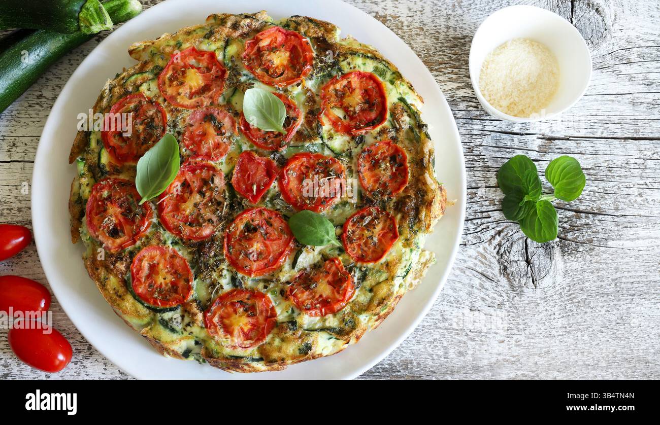 Frittata maison cuite au four avec des légumes tels que courgettes, tomates, œufs et basilic. Nourriture saine. Nourriture estivale. Directement au-dessus. Banque D'Images
