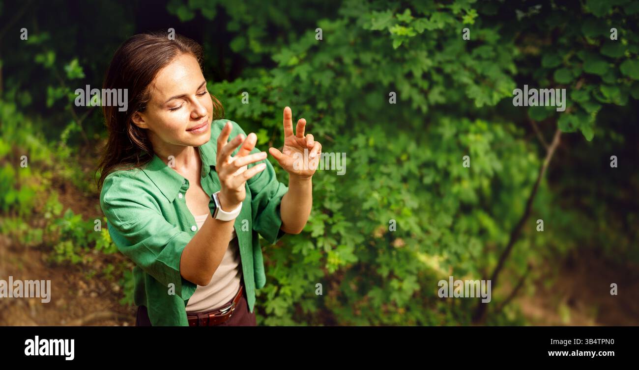 Femme avec les yeux fermés visualisant le flux d'énergie pendant la pratique méditative dans la nature Banque D'Images