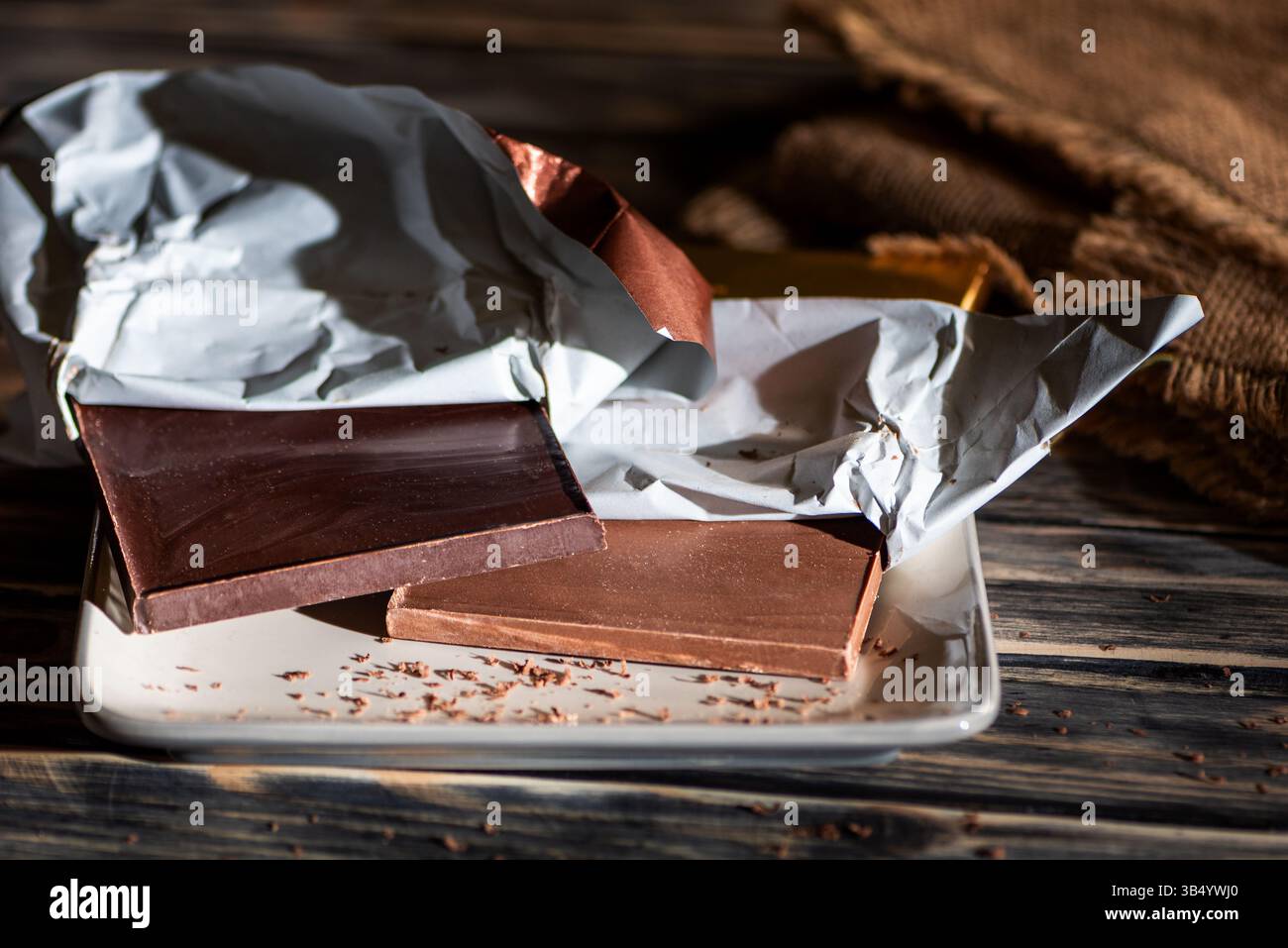 Barres de chocolat noir et au lait sur une assiette, chocolat artisanal, sur une table en bois avec un fond rustique. Banque D'Images