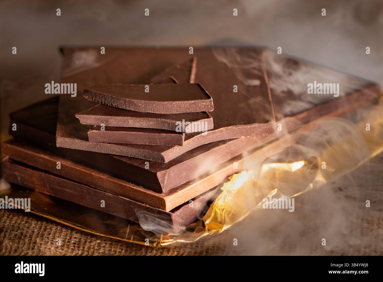 Pile de barres et morceaux de chocolat noir et au lait artisanal, placés les uns sur les autres, entourés de fumée. Banque D'Images