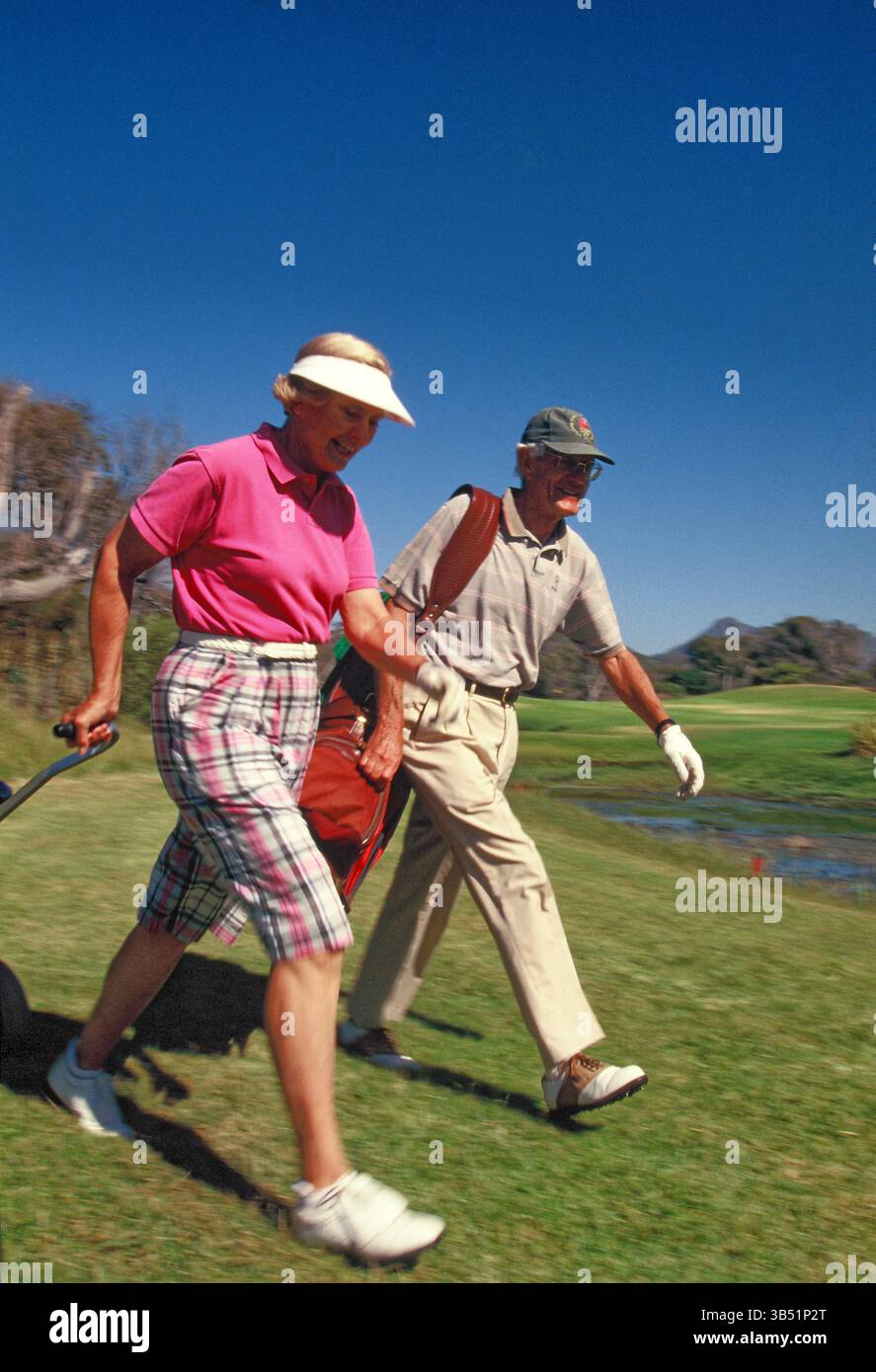 Femmes et hommes seniors golfeurs marchant sur le parcours de golf. Banque D'Images