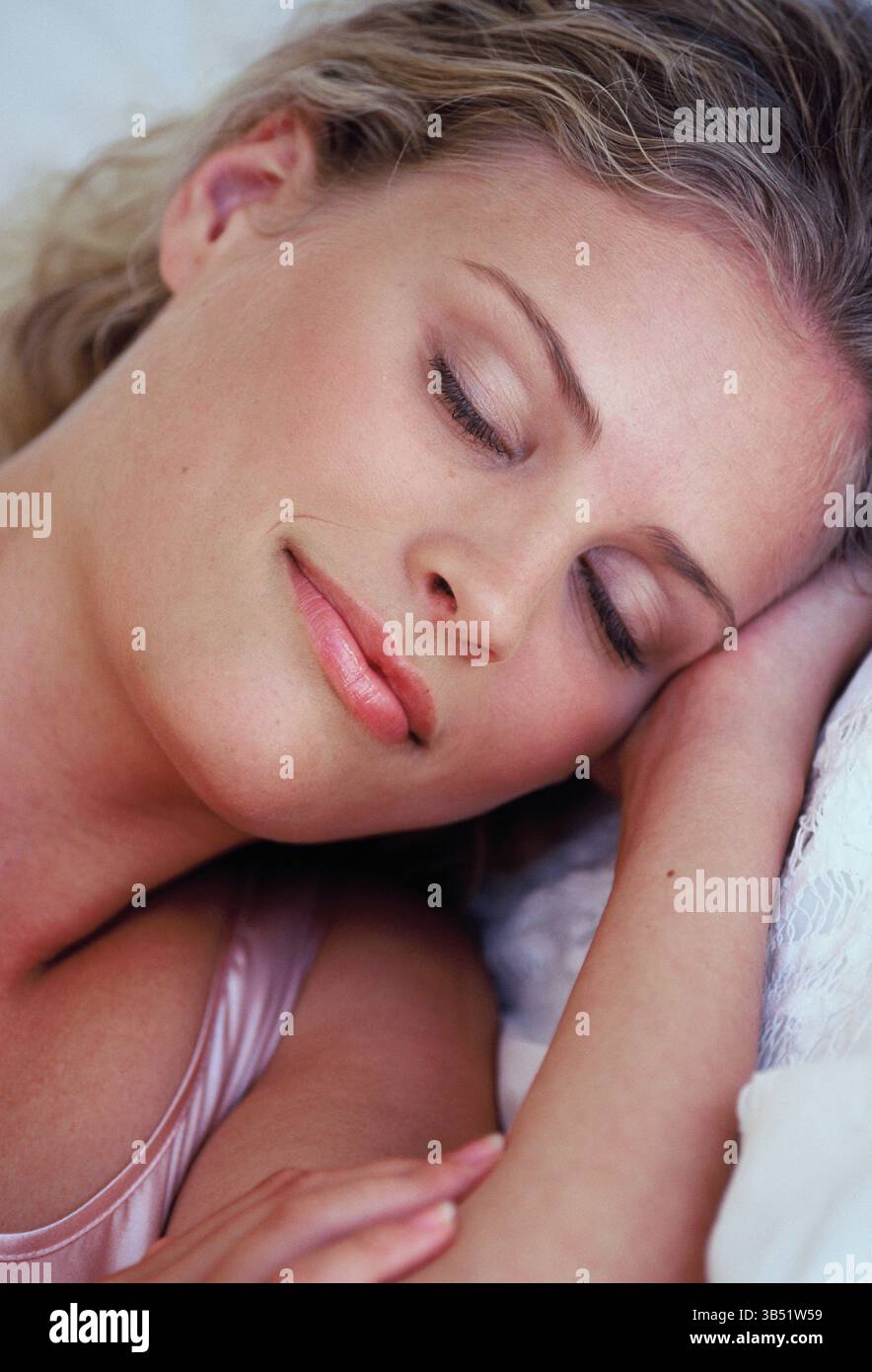 Gros plan de la jeune femme aux cheveux blonds dormant dans le lit. Banque D'Images