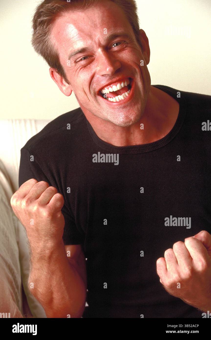 Homme à l'intérieur serrant ses poings en geste de succès. Banque D'Images