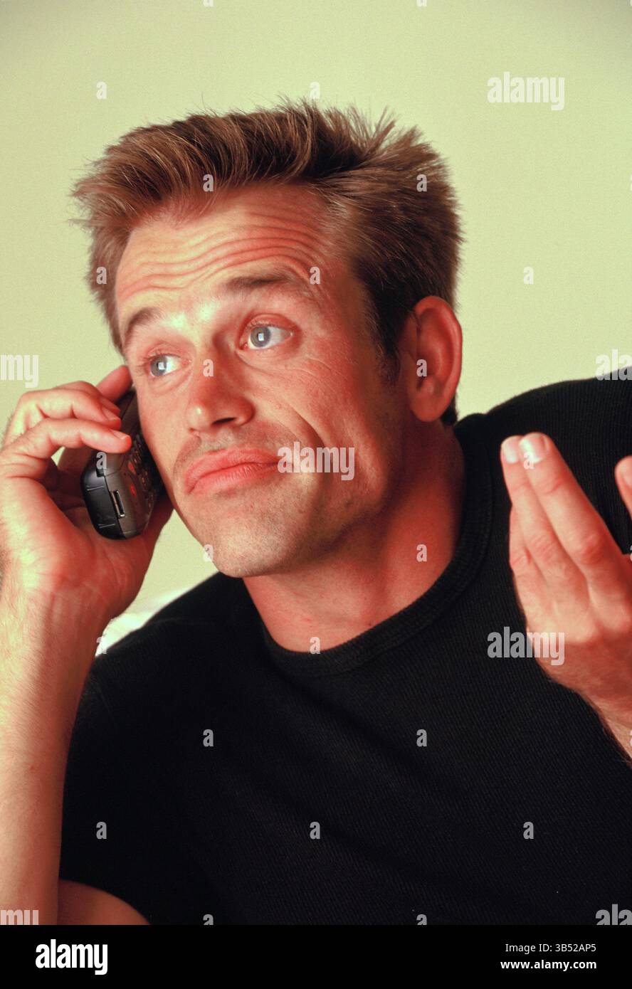 Gros plan de l'homme à l'intérieur parlant sur le téléphone portable brûleur. Banque D'Images
