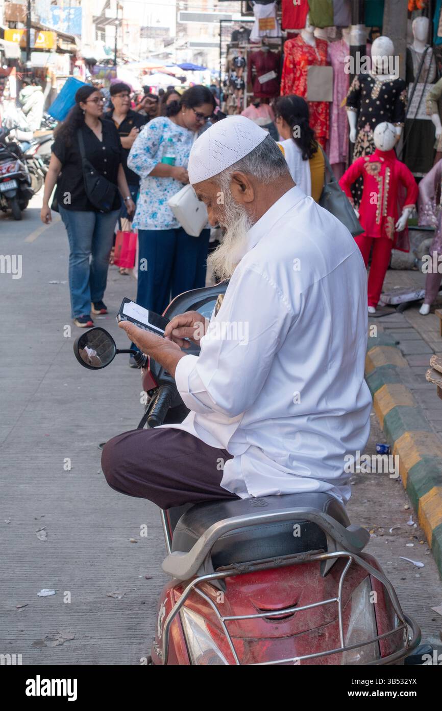Homme musulman assis les jambes croisées sur la moto à Bangalore, Karnataka, Inde, Asie Banque D'Images